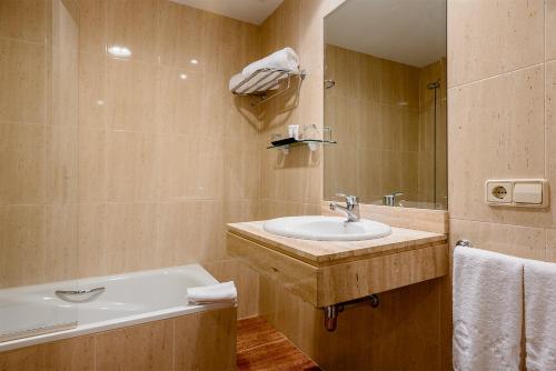 a bathroom with a sink and a tub and a mirror at Ikonik Plaza Mercado in Salamanca