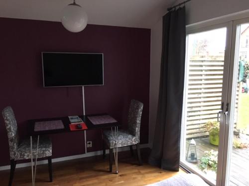 a room with a desk with two chairs and a television at The Garden House in Lund