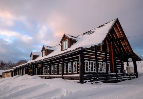 a wooden building with snow on top of it at Margo's Garden Farmstay, Kiroro in Akaigawa