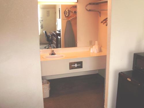 ein Badezimmer mit einem Waschbecken und einem großen Spiegel in der Unterkunft Trade Winds Central Inn in Tulsa