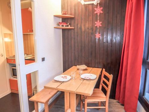une table en bois avec deux chaises et un rideau rouge dans l'établissement Apartment Armoise 51 by Interhome, aux Menuires