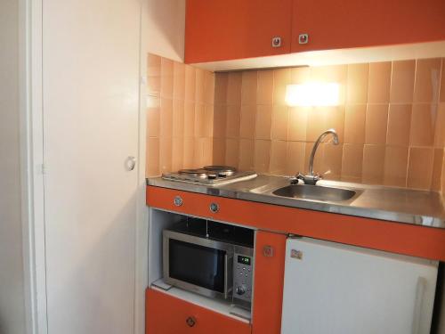 une petite cuisine avec un évier et un micro-ondes dans l'établissement Apartment Armoise 51 by Interhome, aux Menuires