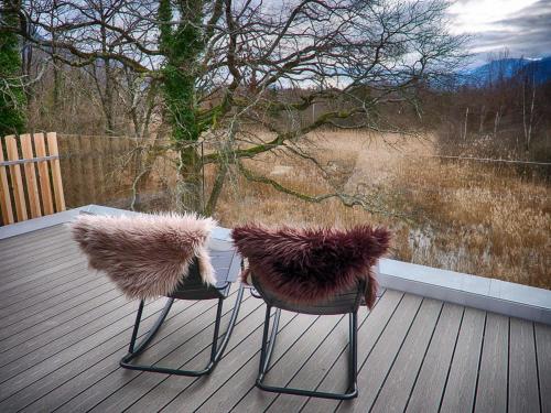 two chairs sitting on a deck with a view at Swiss Lake Lodge in Noville