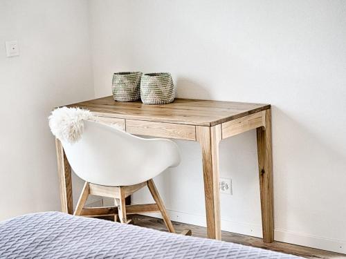 a wooden desk with a white chair next to a bed at Swiss Lake Lodge in Noville