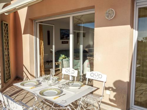 una mesa blanca con sillas y platos. en Apartment Le Stadium-5 by Interhome, en Saint-Cyr-sur-Mer