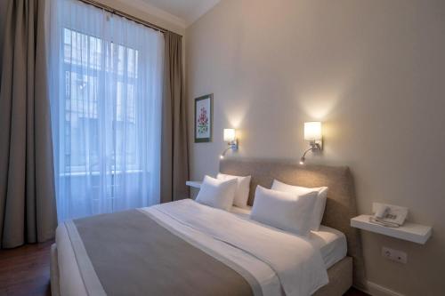 a bedroom with a large bed with a large window at TIFLIS OPERA Aparthotel in Tbilisi City