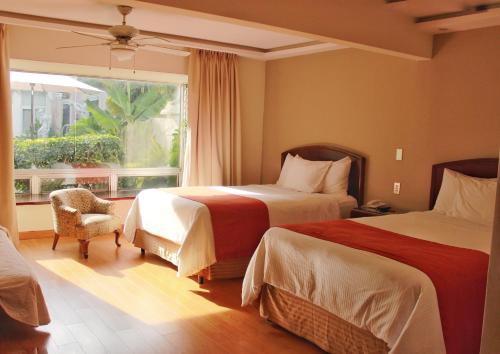 Habitación de hotel con 2 camas y ventana en Hotel San Carlos, en Guatemala