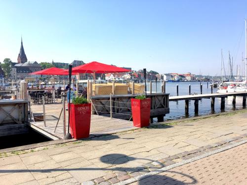 un quai avec deux parasols rouges et un port de plaisance dans l'établissement Holstengang 32 1 Zimmer FEWO, à Flensbourg