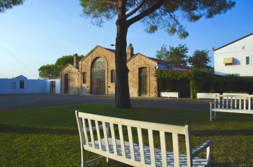 a white bench sitting in front of a church at Masseria Macchia & Relais San Pio in Marina di Pisticci