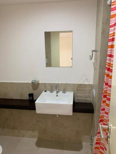 ein Badezimmer mit einem weißen Waschbecken und einem Spiegel in der Unterkunft Potosí 3831 (Almagro Norte) in Buenos Aires