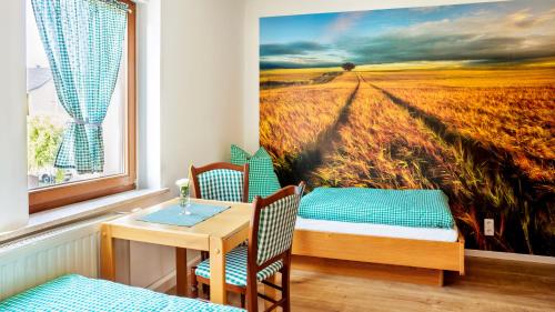 a room with a table and chairs and a painting of a field at Pension Dorfliebe in Sondershausen