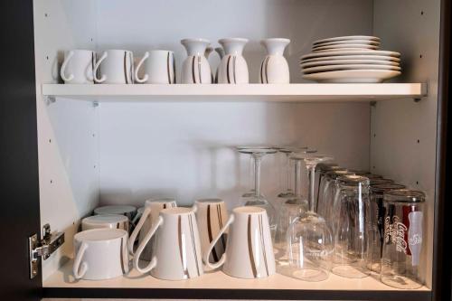 a shelf filled with white dishes and wine glasses at Aktiv Hotel Karnia in Hermagor