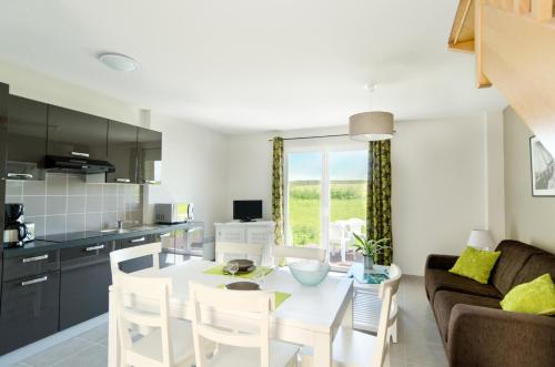 une cuisine et un salon avec une table et des chaises blanches dans l'établissement Résidence Néméa Le Domaine des Mauriers, à Saint-Malo