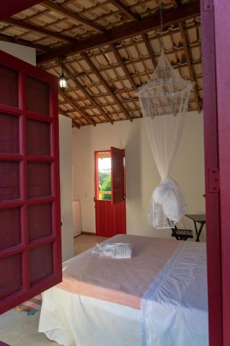 a bedroom with a large bed with a red door at Pousada Vila Sol Maior in Guarapari