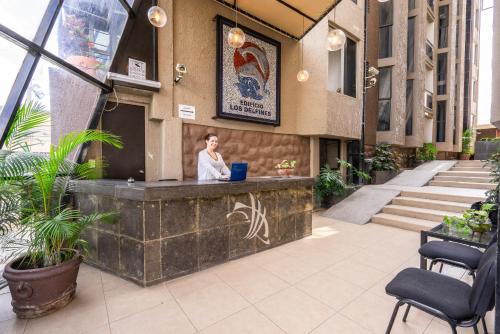 a woman standing at a counter in a building with a laptop at Hotel delf-inn in Cuernavaca