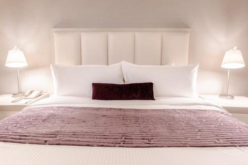 a bedroom with a large white bed with two lamps at Antaris Galerias in Monterrey