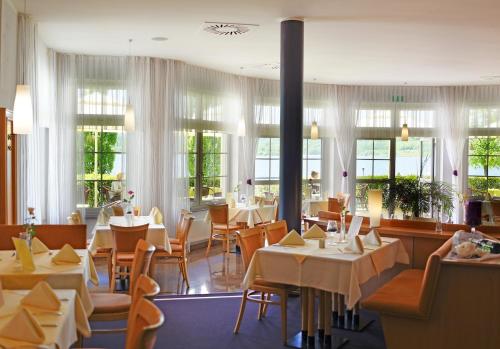 ein Restaurant mit Tischen, Stühlen und Fenstern in der Unterkunft Hotel Haus am See in Olbersdorf