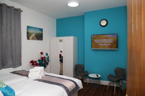 a bedroom with blue walls and a bed with two chairs at Birmingham Central Station Apartment (Flat 5) in Birmingham