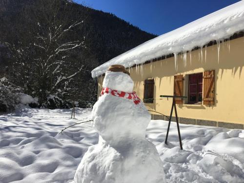 Ein Schneemann steht vor einem Haus in der Unterkunft Gîte Espace et Montagne in Aragnouet