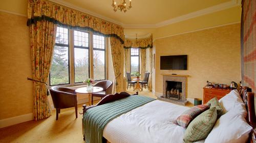 a bedroom with a bed and a desk and a fireplace at Kincraig Castle Hotel in Invergordon