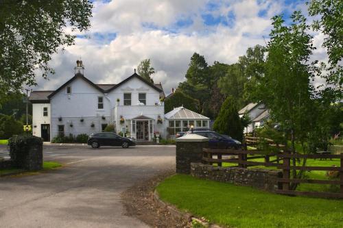 una casa blanca con un coche aparcado delante de ella en The White House, en Sennybridge