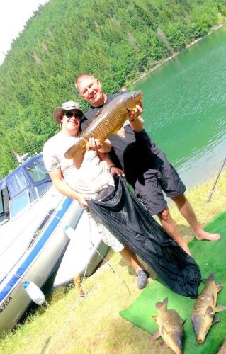 two men are holding a fish in front of a boat at Vila Jelena Zlatar Nova varoš in Brdo