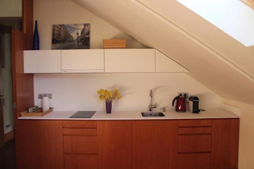 uma cozinha com armários brancos e um lavatório debaixo de uma escada em A casa Rosa- Ático en el centro de Vigo em Vigo
