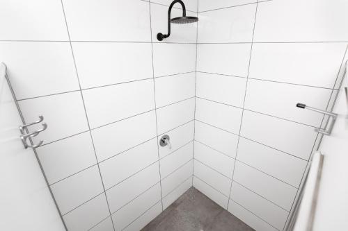 a bathroom with a shower with white tiles at Mad Monkey Jungle in Cairns