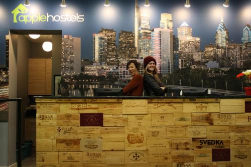 two women standing behind a counter with a city skyline at Apple Hostels of Philadelphia in Philadelphia