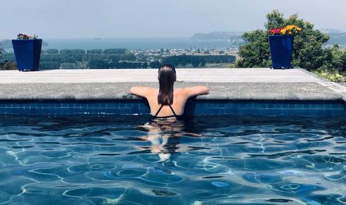 una mujer está sentada en una piscina en WoodyHanger Lodge, en Whitianga