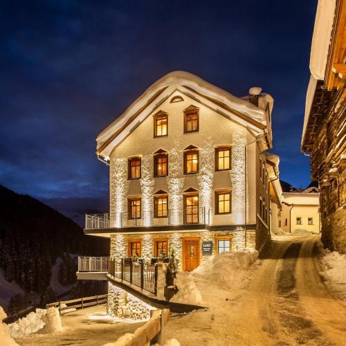 a large house with a snow covered roof at LARET private Boutique Hotel - Adults only in Samnaun