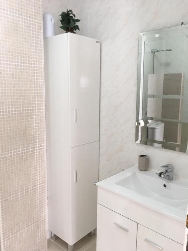 ein weißes Badezimmer mit Waschbecken und Spiegel in der Unterkunft Apartamento Pasaje Ronda Centro in Ronda