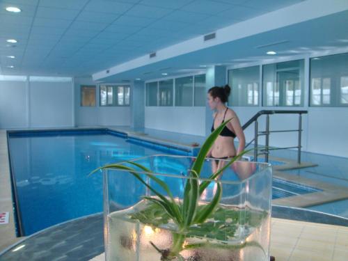 a woman in a bikini standing next to a swimming pool at Constantzia Balneohotel in Kostenets