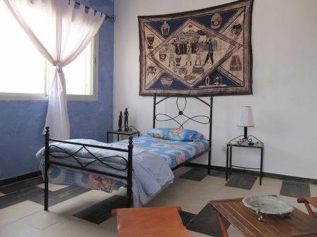 a bedroom with a bed and a painting on the wall at EDEN BEACH SAINT-LOUIS in Saint-Louis
