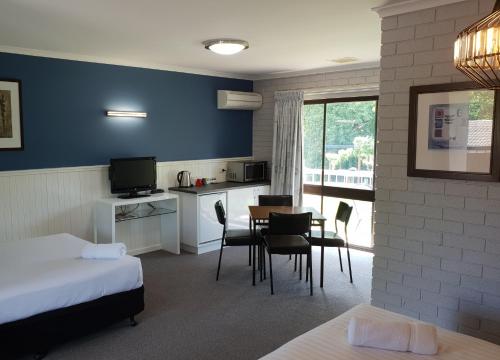 a room with a table, chairs, and a television at Motel Sierra formerly Bogong View in Bright