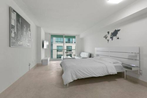 ein weißes Schlafzimmer mit einem großen Bett und einem Fenster in der Unterkunft Centric Modern, Stylish Brickell / Miami + FREE Parking in Miami