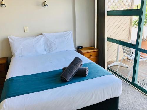 a bedroom with a bed with a towel on it at Aquarius Motel in Ohope Beach