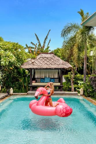 a young girl is riding on a pink raft in a pool at Mayo Resort in Umeanyar