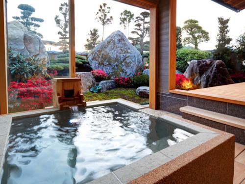 a swimming pool in a garden with a rock at Ryokan Shinsen in Takachiho