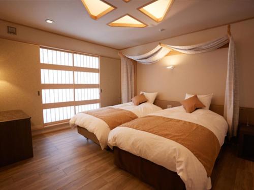 two beds in a bedroom with a large window at Ryokan Shinsen in Takachiho