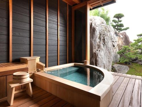a jacuzzi tub in a house with a waterfall at Ryokan Shinsen in Takachiho
