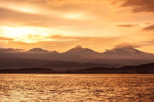 a sunset over the water with mountains in the background at Mayo Resort in Umeanyar