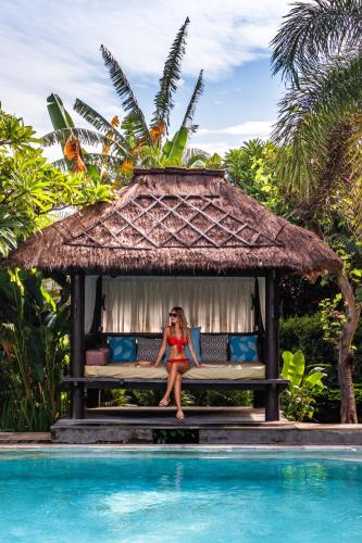 a woman sitting on a bench next to a swimming pool at Mayo Resort in Umeanyar