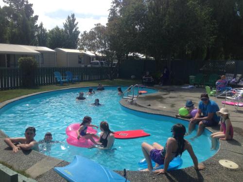 un grupo de personas sentadas en una piscina en Glenmark Holiday Park, en Timaru