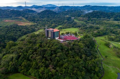 an aerial view of a building on a hill with trees at Summit Rainforest Golf Resort & All Inclusive in Paraíso
