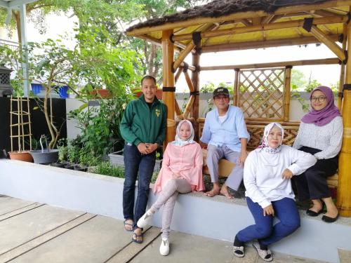 a group of people sitting on a bench in a gazebo at INNI Homestay in Malang