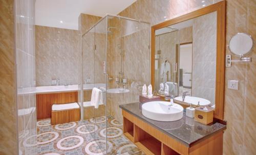 a bathroom with a sink and a shower and a mirror at Sunset Palace View Suites in Mandalay