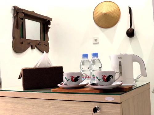 a counter with two cups and water bottles on it at The LaWang Yogya Guesthouse in Yogyakarta