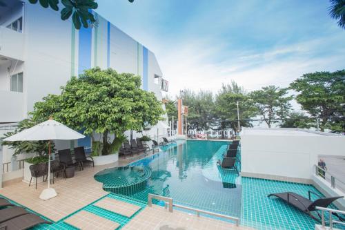 a swimming pool in a hotel with chairs and an umbrella at Asia Cha-am Hotel in Cha Am