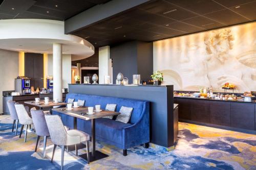 a restaurant with blue walls and tables and chairs at Best Western Plus Hotel & Restaurant Les Humanistes Colmar Nord in Sélestat